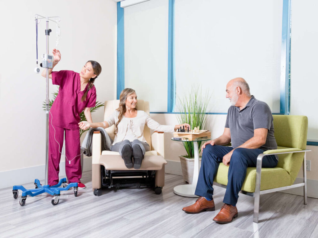 Infusion patient playing chess with a visitor while receiving IV therapy